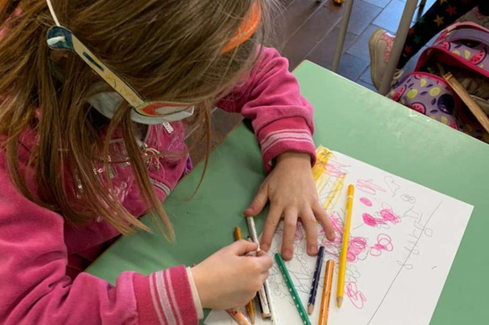 bambina disegna con matite colorate