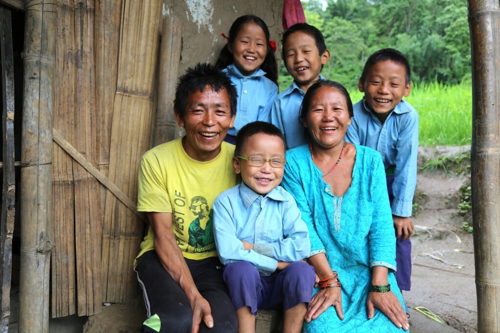 sudip sorride con gli occhiali da vista seduto insieme alla sua famiglia