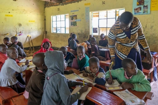 classe di bimbi e bimbe a scuola con bimba che fatica a leggere bene cosa c'è scritto sulla lavagna