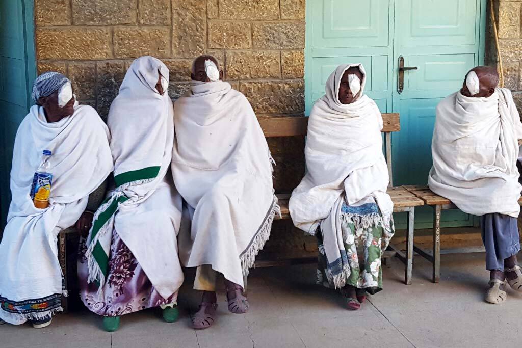 donne sedute su una panca con un cerotto sull'occhio