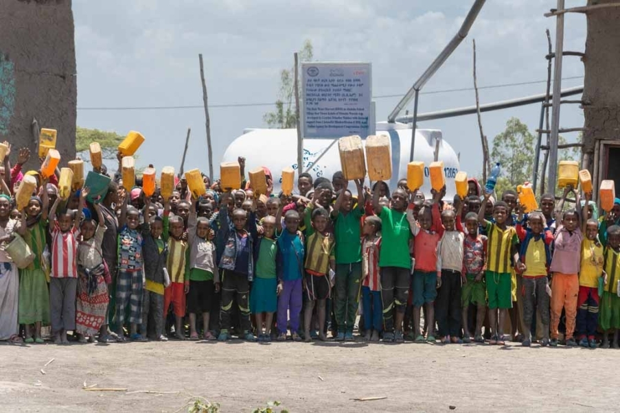 gruppo di bambini con taniche gialle per l'acqua