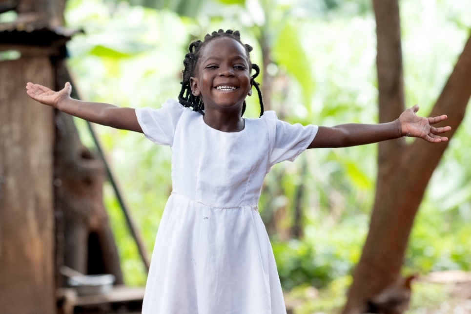 bimba con vestito bianco sorride a braccia spalancate